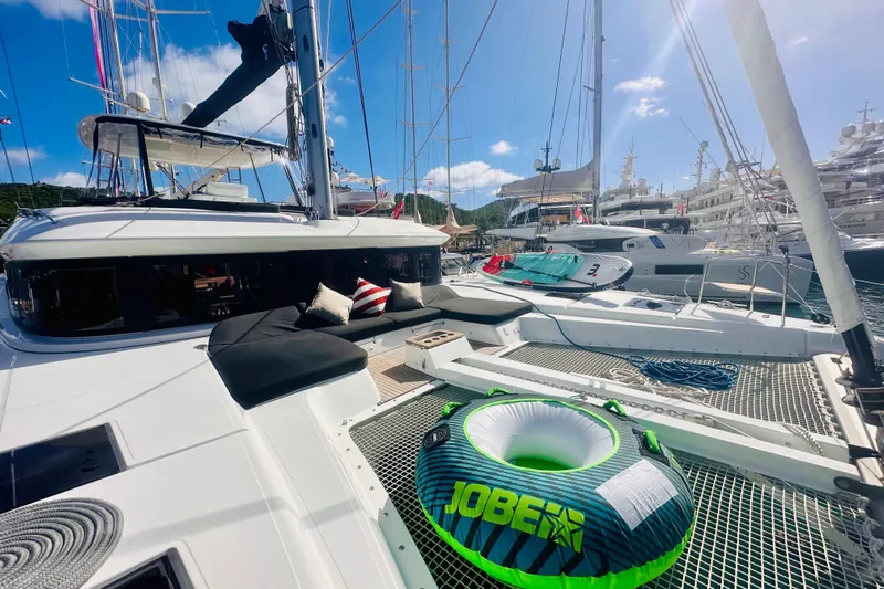  Yacht Photos Pics 2024 Lagoon 51 yacht with lounging area and inflatable tube in a marina.