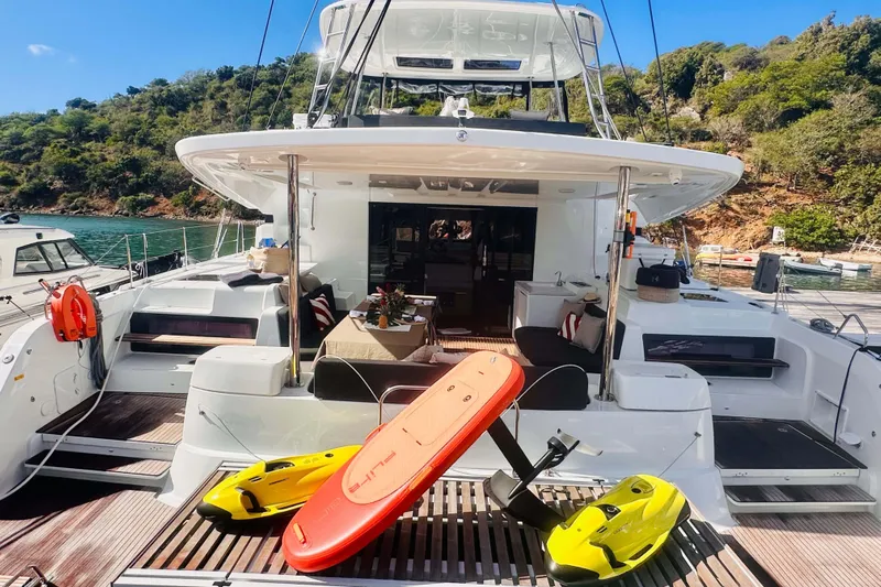  Yacht Photos Pics 2024 Lagoon 51 yacht with water sports equipment, docked in a scenic bay.