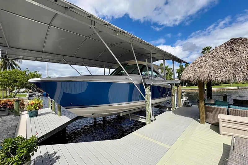 Liquid Asset Yacht Photos Pics 2024 Tiara Yachts 34 LX on a covered dock, surrounded by tropical scenery.