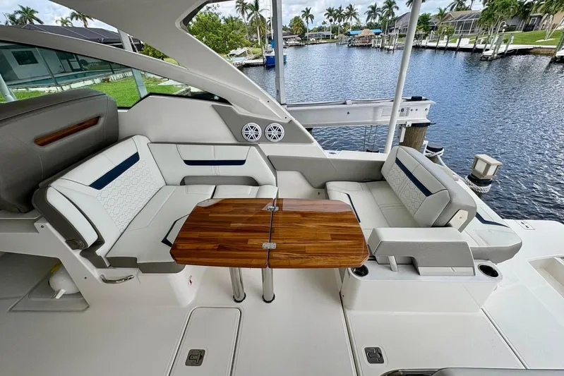Liquid Asset Yacht Photos Pics Luxurious seating area on 2024 Tiara Yachts 34 LX, featuring elegant wood table and waterfront view.