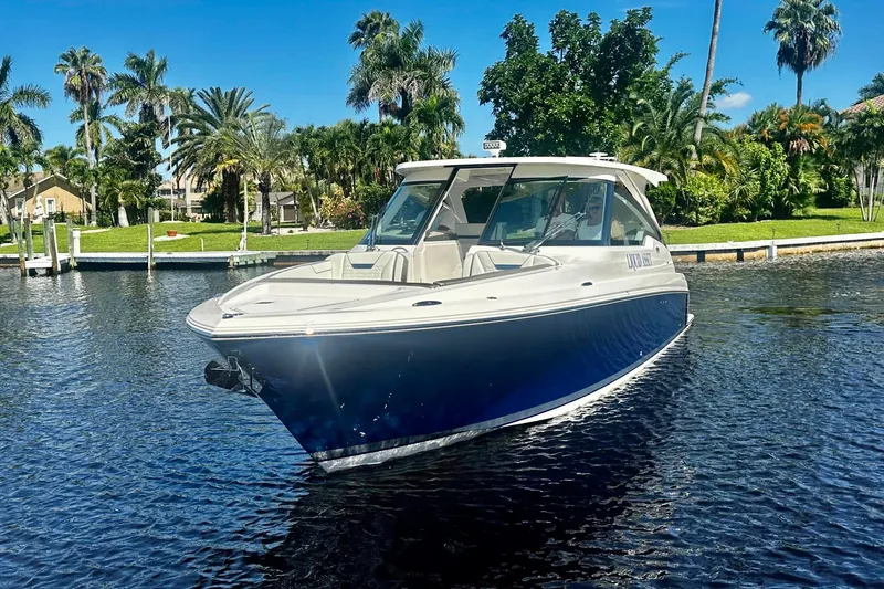 Liquid Asset Yacht Photos Pics 2024 Tiara Yachts 34 LX boat on a sunny day, surrounded by lush greenery.