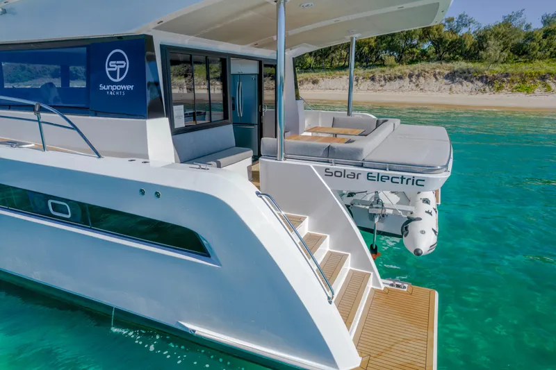  Yacht Photos Pics Sunpower 44 VIP 2022 solar electric yacht on clear turquoise water near sandy beach.