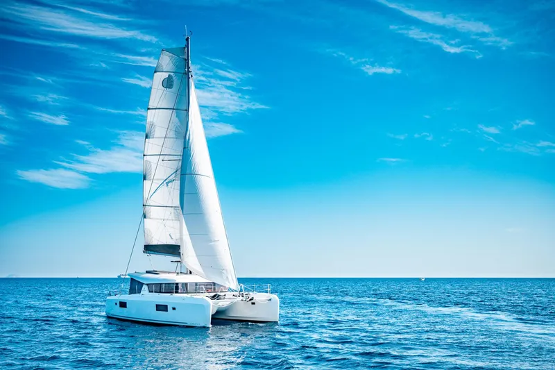  Yacht Photos Pics 2018 Lagoon 42 catamaran sailing on open sea under clear blue sky.