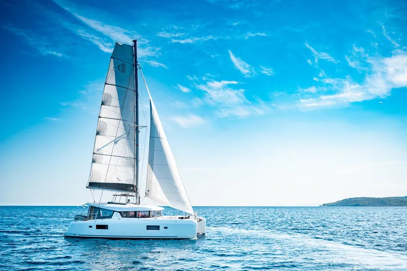  Yacht Photos Pics 2018 Lagoon 42 catamaran sailing on open sea under clear blue sky.