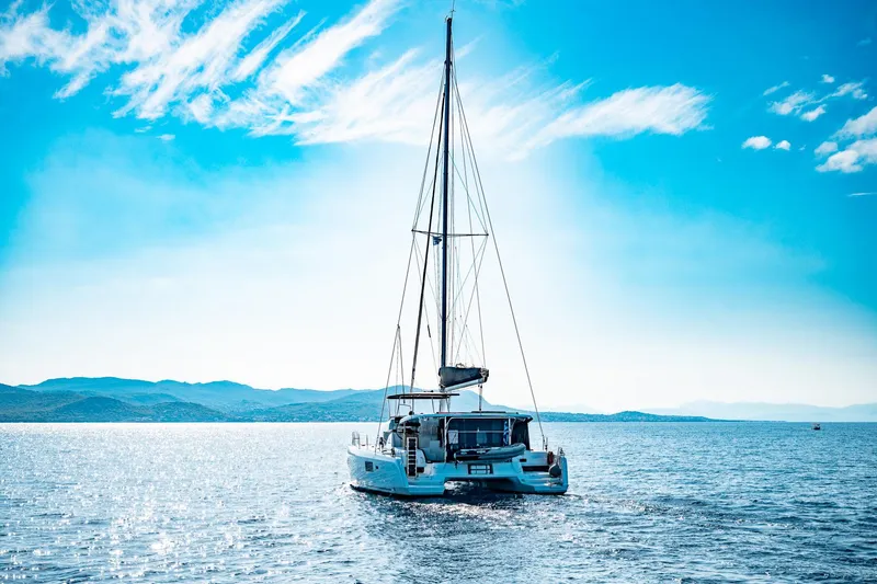  Yacht Photos Pics 2018 Lagoon 42 catamaran sailing on a sunny day with scenic ocean backdrop.