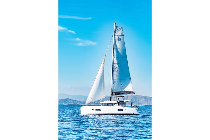  Yacht Photos Pics 2018 Lagoon 42 catamaran sailing on clear blue ocean under sunny sky.