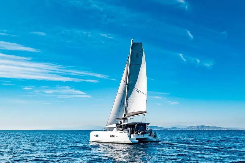  Yacht Photos Pics 2018 Lagoon 42 catamaran sailing on open sea under clear blue sky.