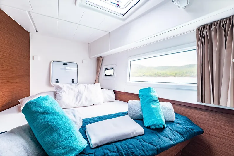  Yacht Photos Pics Cozy cabin interior of 2018 Lagoon 42 yacht with neatly arranged towels and scenic window view.