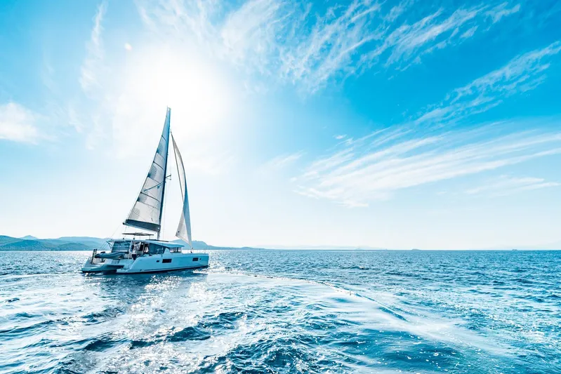  Yacht Photos Pics 2018 Lagoon 42 catamaran sailing on open sea under clear blue sky.