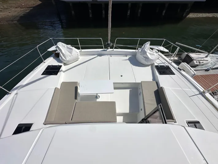 After You Yacht Photos Pics 2023 Bali 4.2 yacht deck with seating and table, docked by the water.