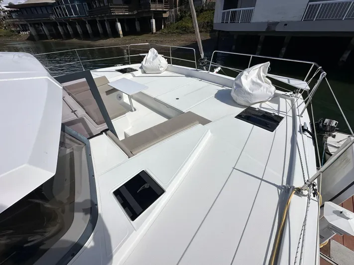 After You Yacht Photos Pics 2023 Bali 4.2 yacht deck with seating and hatches, docked near waterfront homes.