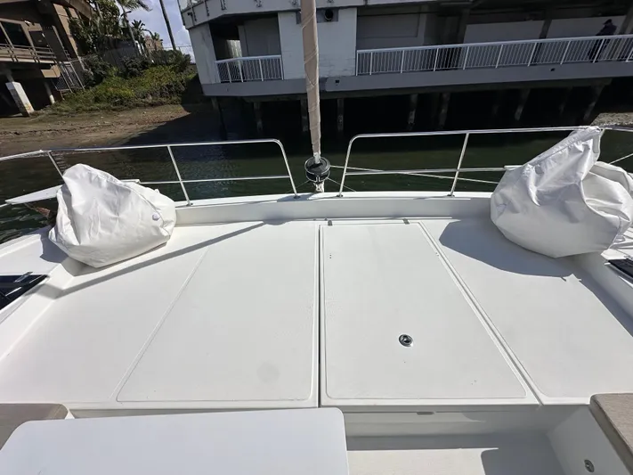 After You Yacht Photos Pics Deck of 2023 Bali 4.2 yacht with white cushions, docked near a building.