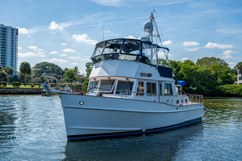  Yacht Photos Pics Grand Banks 42 Classic 2002 yacht on calm water, with clear sky and greenery.