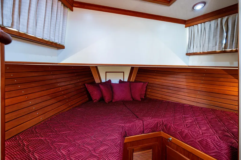  Yacht Photos Pics Cozy cabin interior of 2002 Grand Banks 42 Classic with rich wood paneling and red bedding.