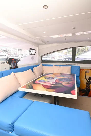  Yacht Photos Pics Interior of 2017 Leopard 51 Powercat with vibrant artwork on table and blue seating.