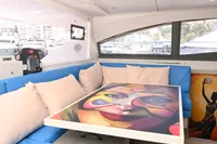Interior of 2017 Leopard 51 Powercat with vibrant artwork on table and blue seating.