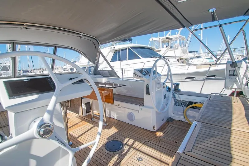  Yacht Photos Pics 2021 Bavaria C45 yacht cockpit with dual steering wheels and teak flooring in marina setting.