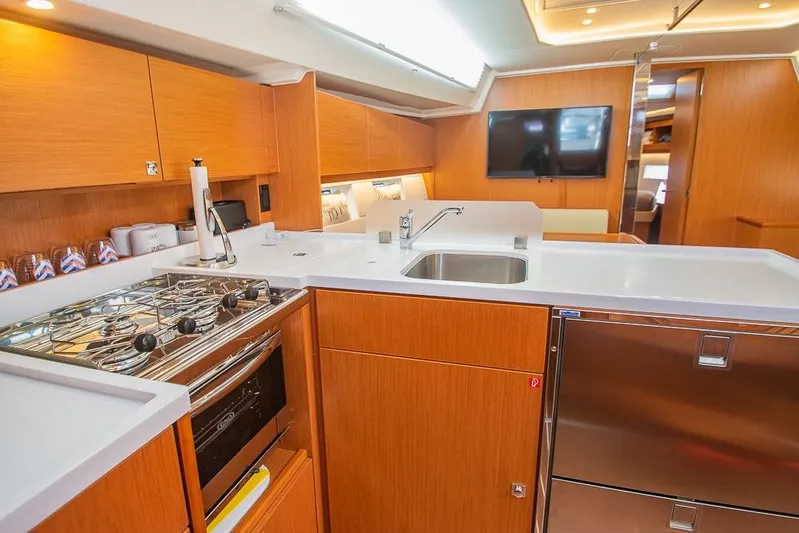  Yacht Photos Pics Modern kitchen interior of 2021 Bavaria C45 yacht with wooden cabinetry and stainless steel appliances.