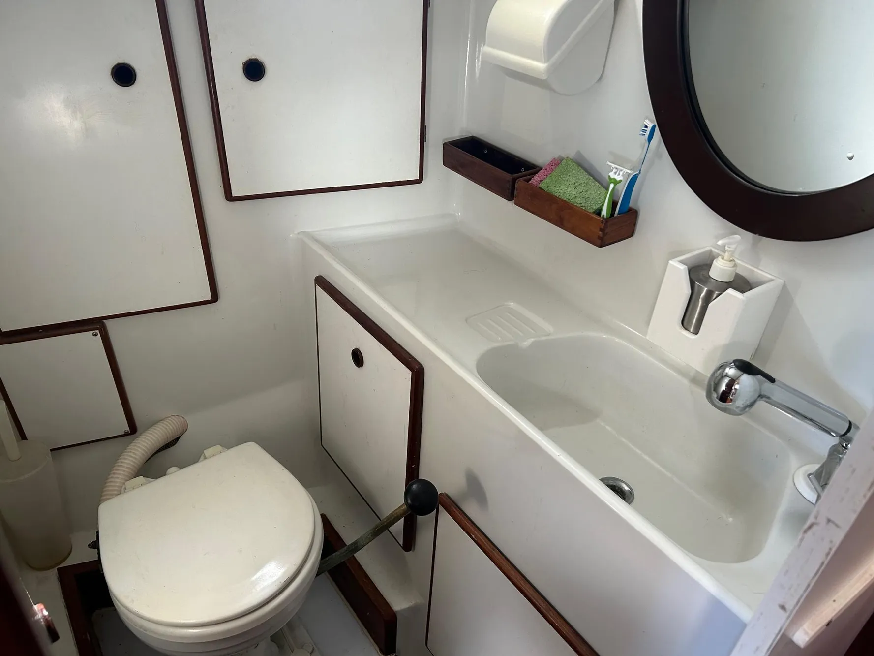 1975 Salar 40 yacht bathroom with sink, toilet, mirror, and storage cabinets.