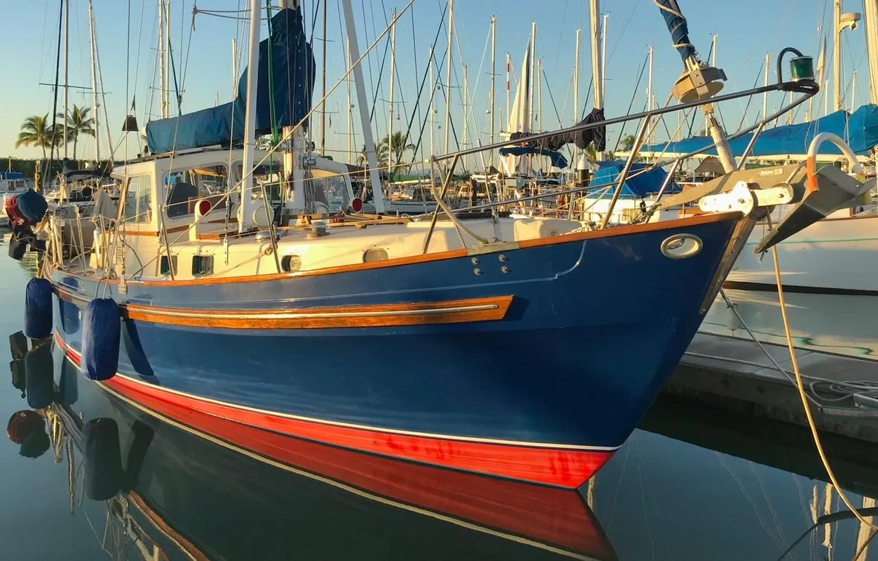 1975 Salar 40 sailboat docked in marina, blue hull with red stripe, sunny day.