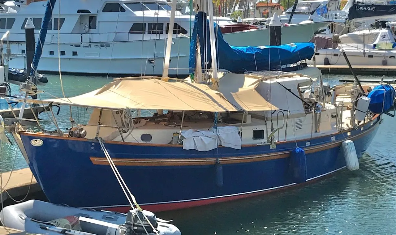 1975 Salar 40 sailboat docked in marina, featuring blue hull and tan canopy.