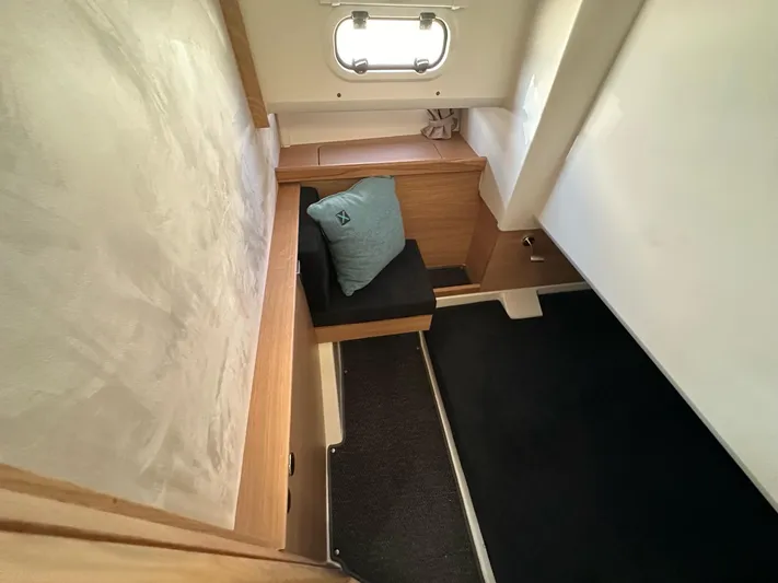 Mdr #187 In Stock Yacht Photos Pics 2023 Nimbus T11 cabin interior with wooden accents, black seating, and a small window.