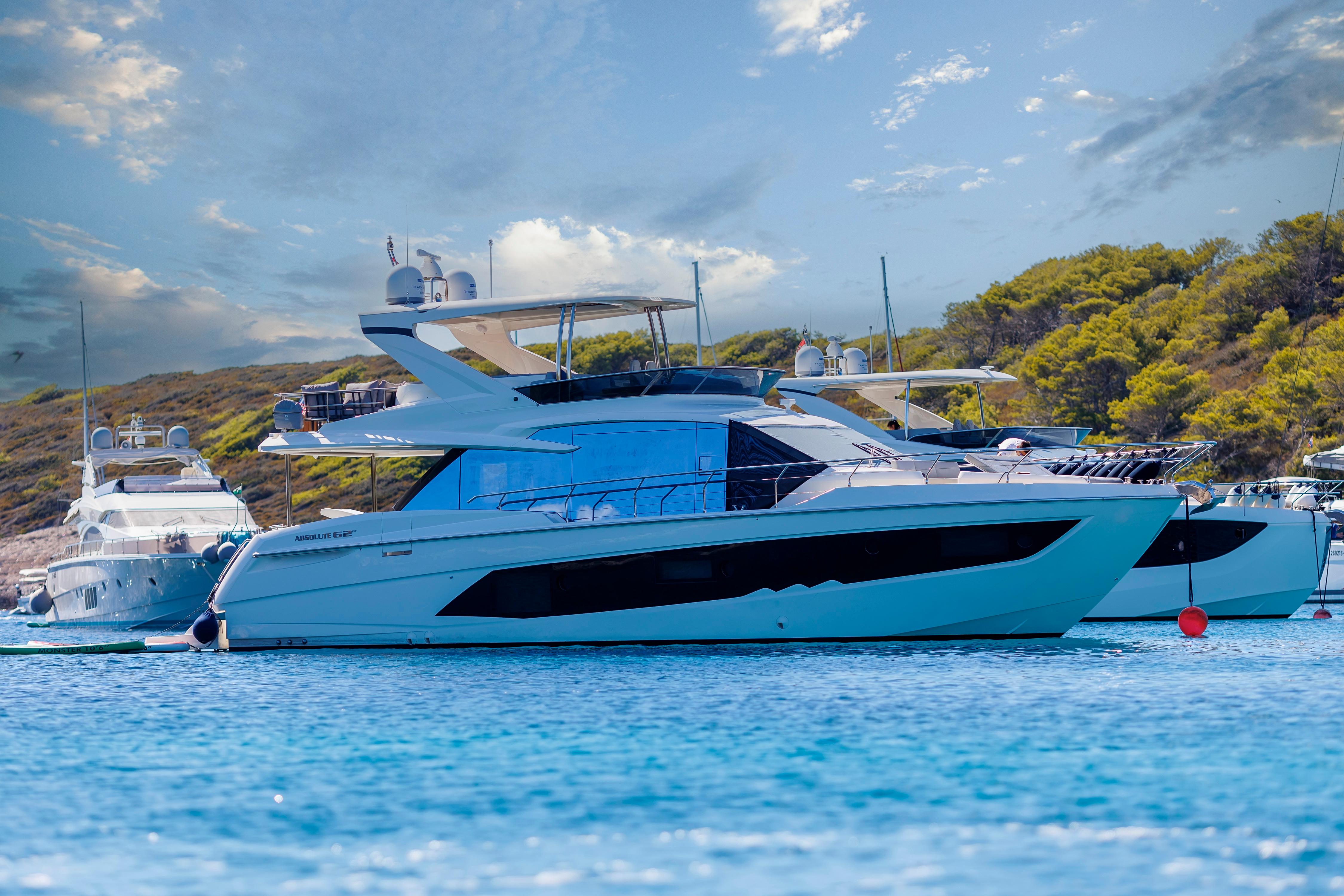 Luxury yacht "Absolute Fly Co Ownership" 2023 on serene blue waters, scenic backdrop.