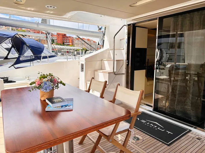 Tamara II Yacht Photos Pics Outdoor dining area on 2018 Azimut 66 FLY yacht with table, chairs, and floral centerpiece.