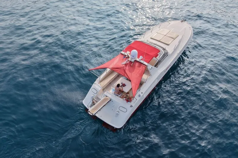  Yacht Photos Pics 1989 Riva 51 Turborosso yacht with red canopy cruising on open water.