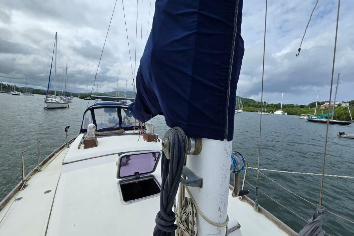 1982 Reliance 44 sailboat on calm water with cloudy sky background.