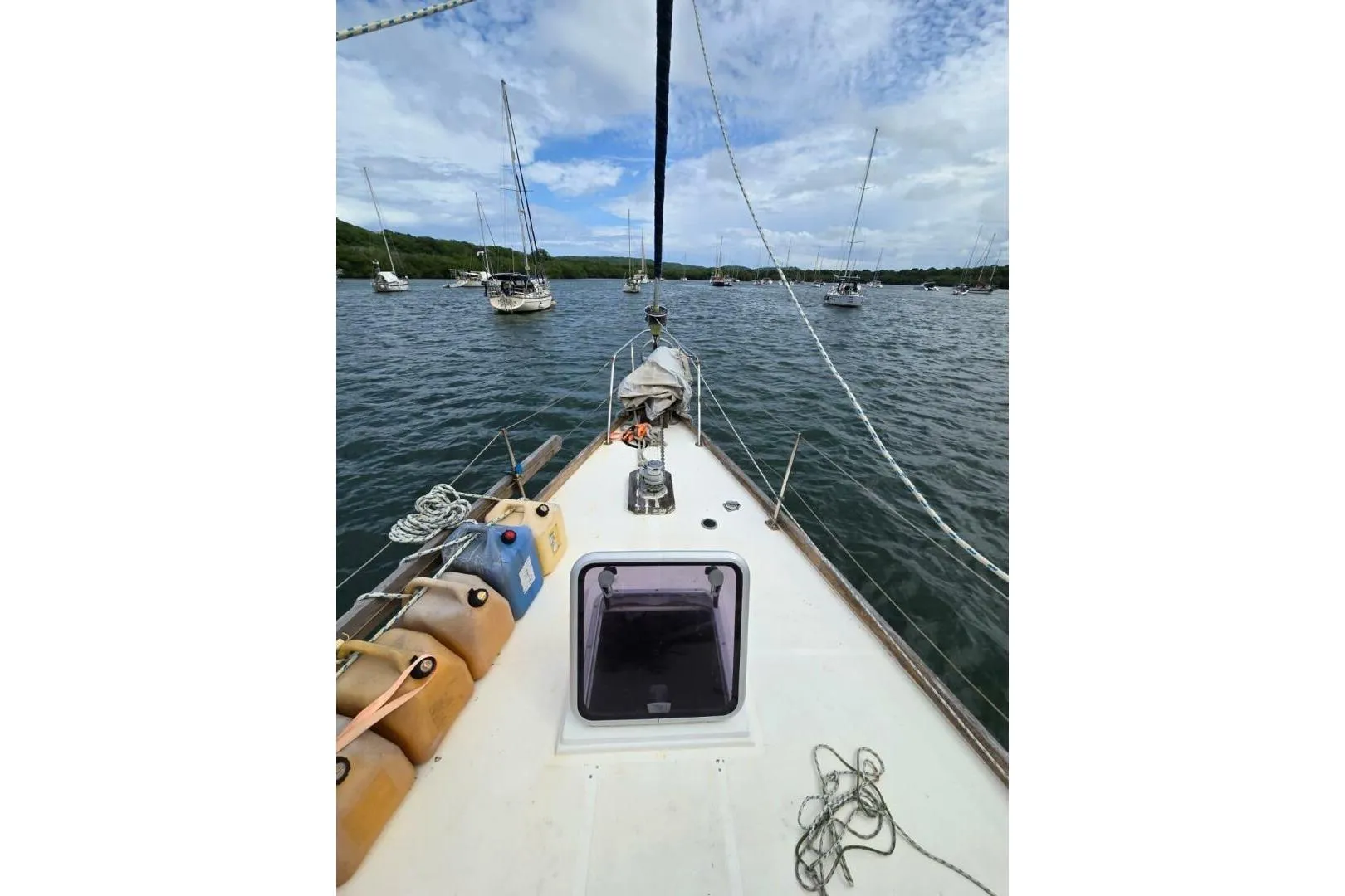 Sailboat deck view on water, Reliance 44, 1982 model, with moored boats in background.