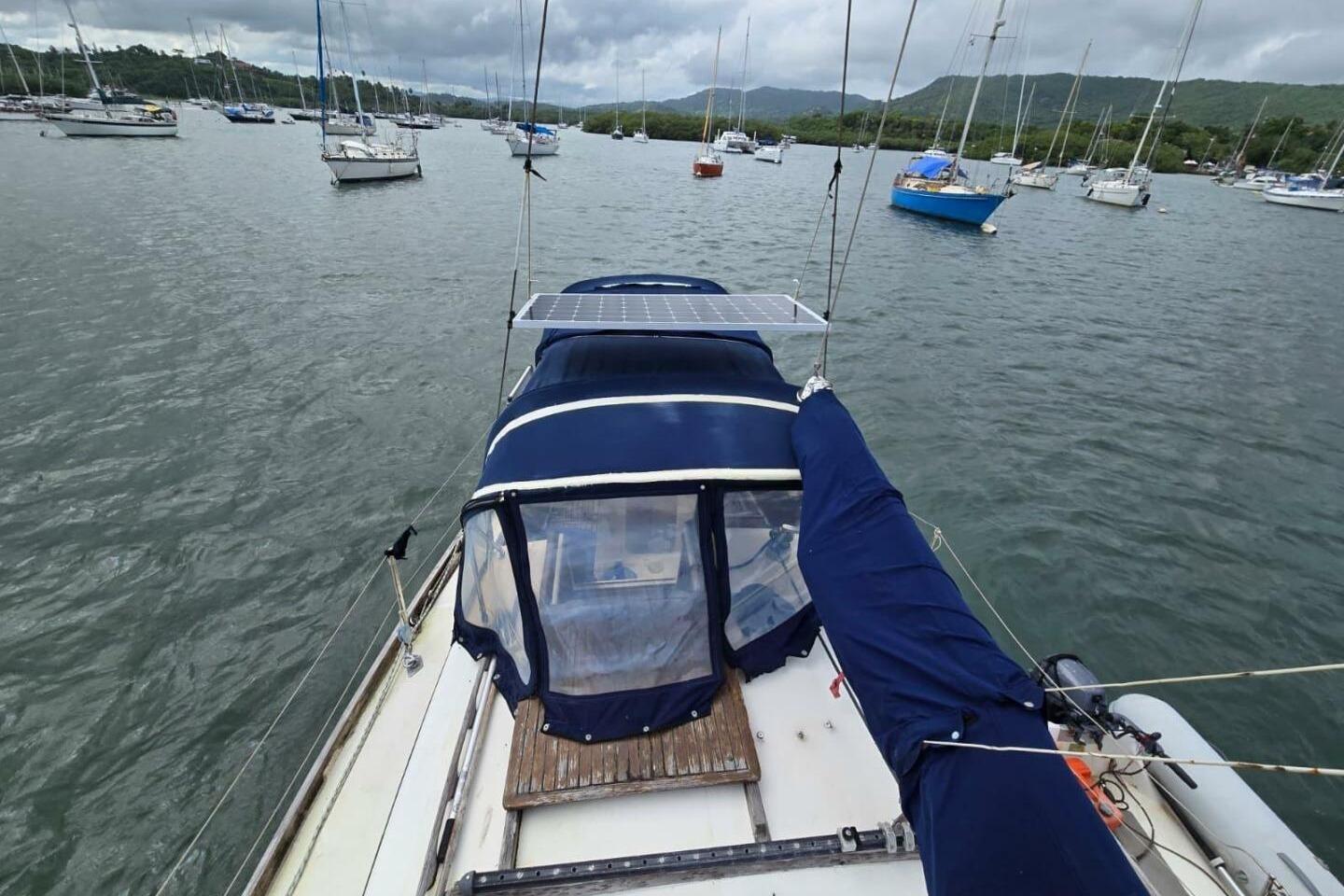 Sailboat on water with solar panel, surrounded by other boats; Reliance 44, 1982 model.