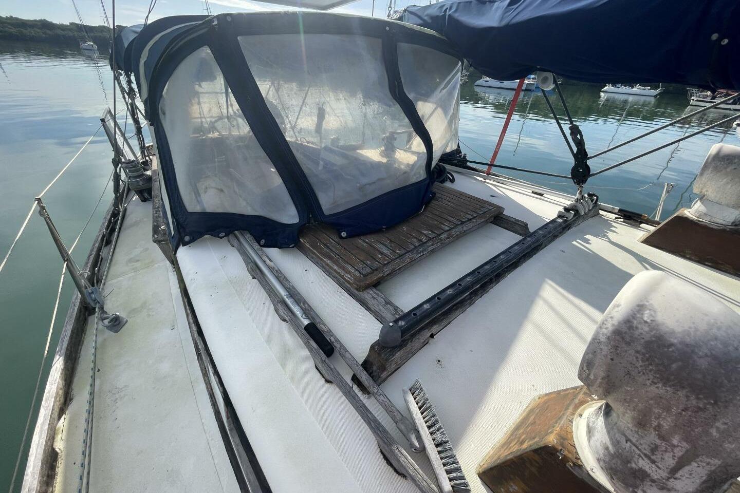 1982 Reliance 44 sailboat deck with canopy, docked on calm water.