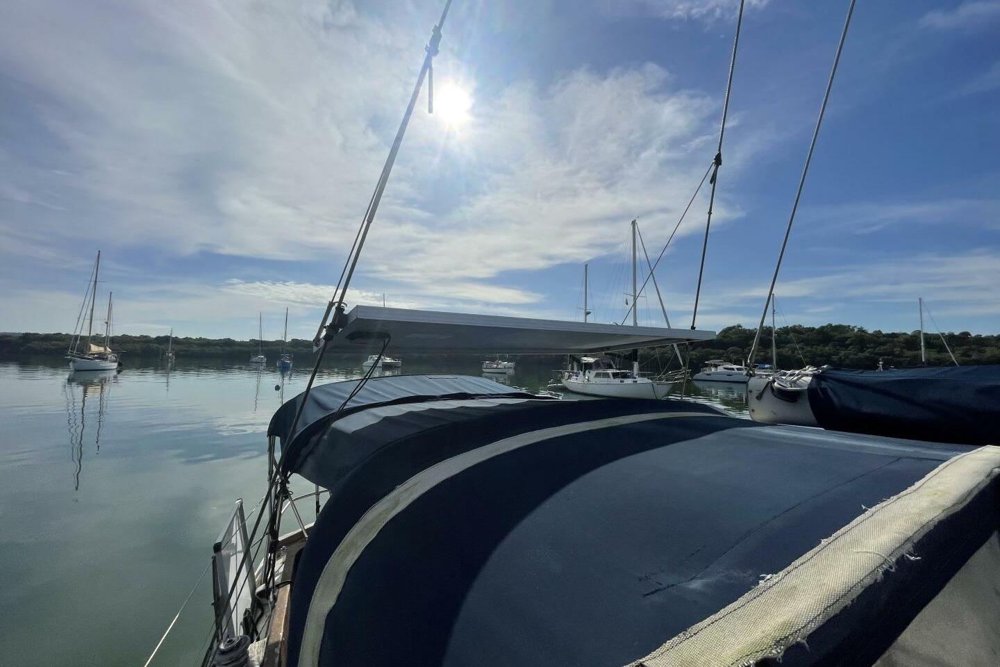 Sailboat on calm water, Reliance 44, 1982, with clear sky and distant boats.