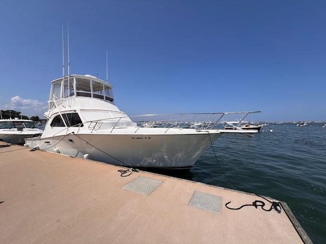 1985 Post 43 Convertible yacht docked at marina under clear blue sky.