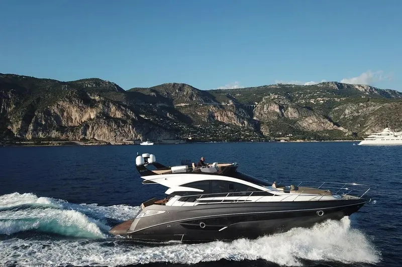  Yacht Photos Pics Luxurious 2025 Cobrey 52 FLY yacht cruising near scenic coastal cliffs.