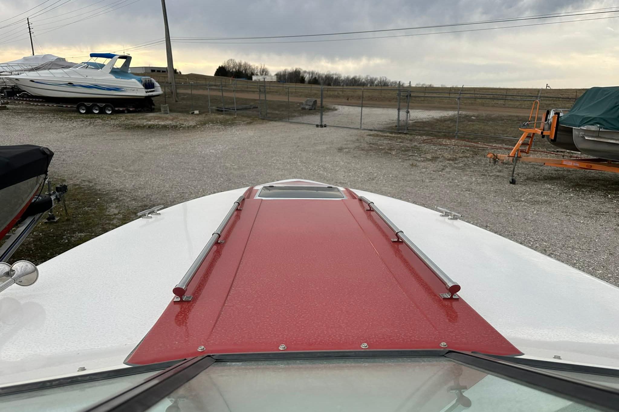 1987 IMP 255 Eleganza boat with red and white deck, parked outdoors.