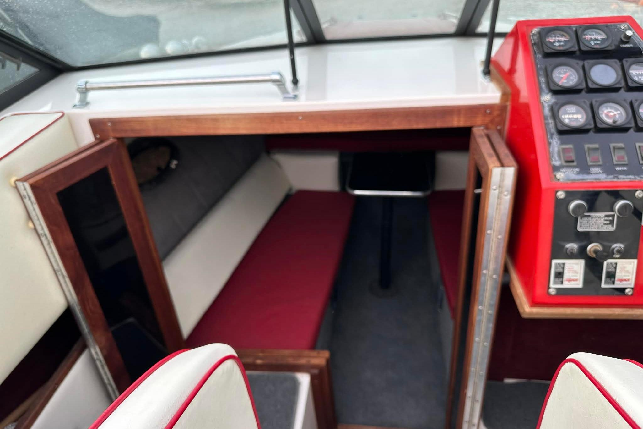 1987 IMP 255 Eleganza boat interior with red dashboard and cozy cabin seating.