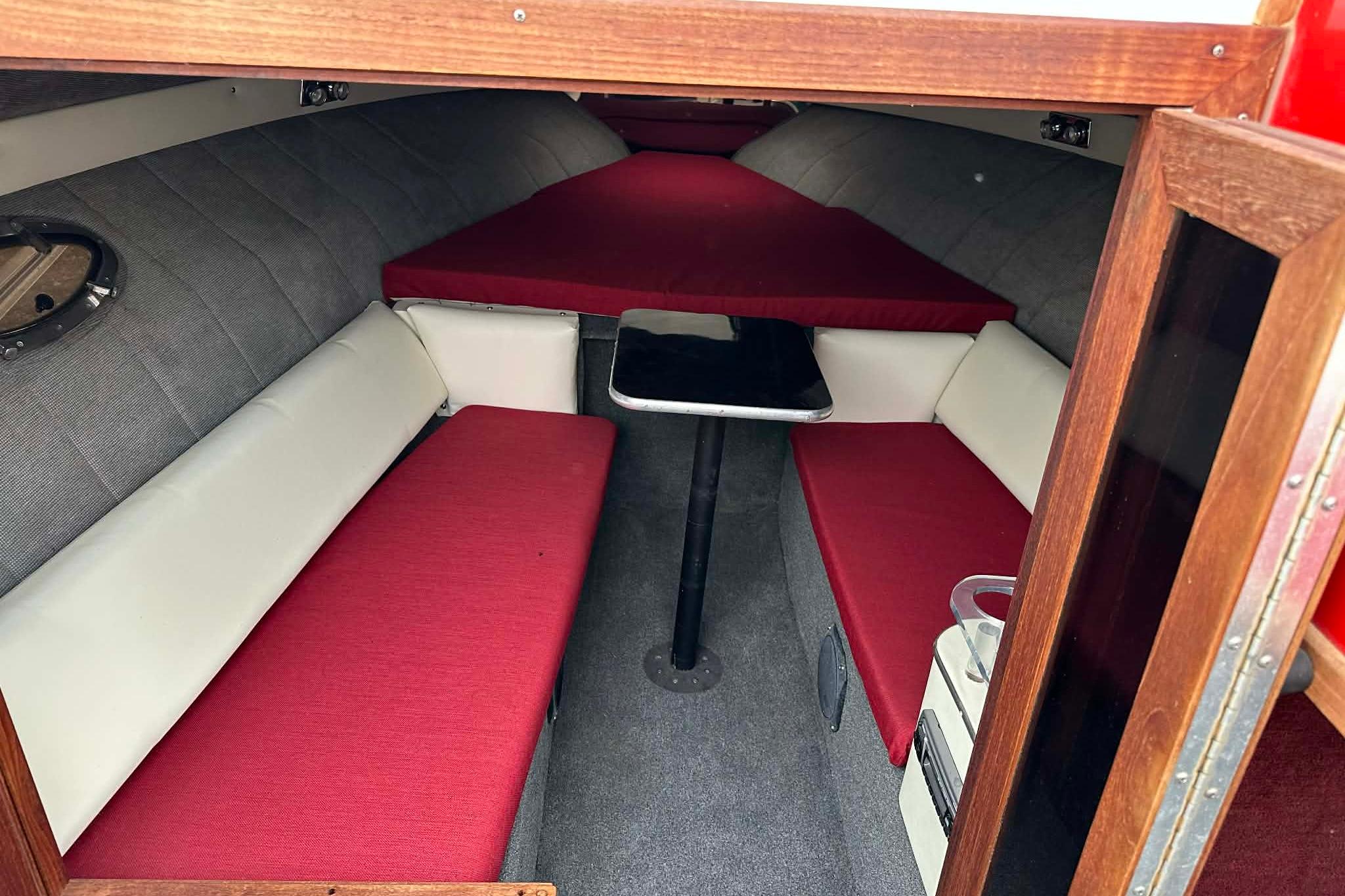1987 IMP 255 Eleganza boat interior with red and white seating, small table, and cozy cabin.
