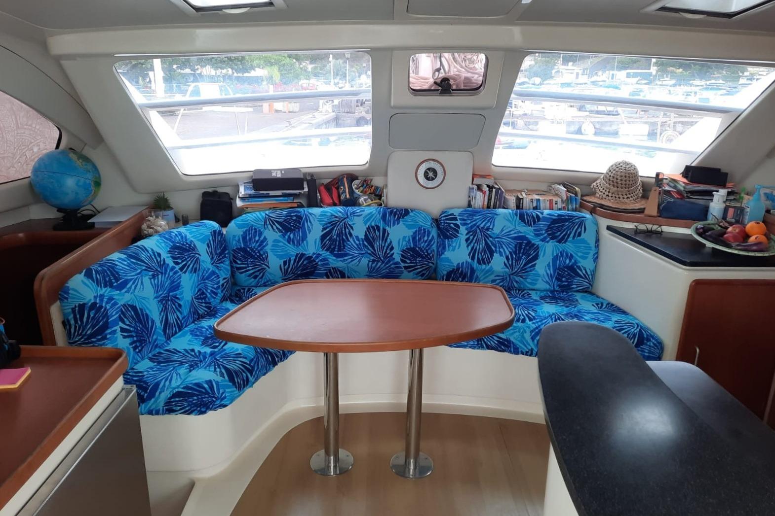 Interior of a 2006 Leopard 40 catamaran with blue leaf-patterned seating and wooden table.