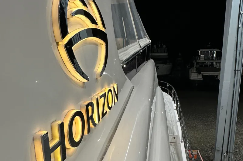  Yacht Photos Pics Horizon PC60 yacht, 2017 model, illuminated logo at night in a marina setting.