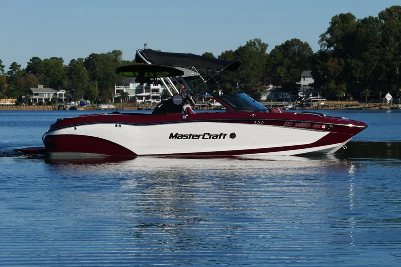  Yacht Photos Pics 2022 MasterCraft X22 boat on a calm lake with scenic background.