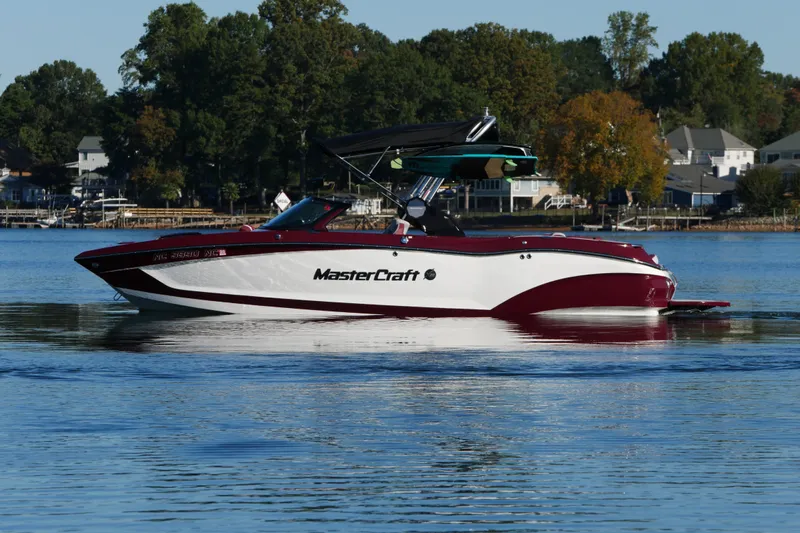  Yacht Photos Pics 2022 MasterCraft X22 boat on a calm lake with trees in the background.