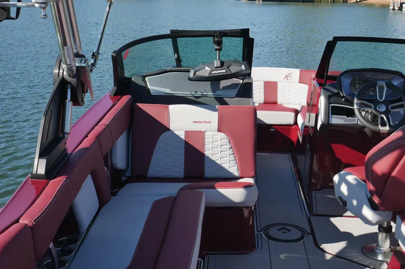  Yacht Photos Pics 2022 MasterCraft X22 boat interior with red and white seating, steering wheel, and lake view.