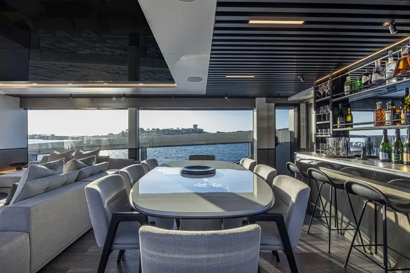 Pearly Spencer Yacht Photos Pics Luxurious interior of 2024 Pearl 82 yacht with dining area and bar, overlooking the sea.