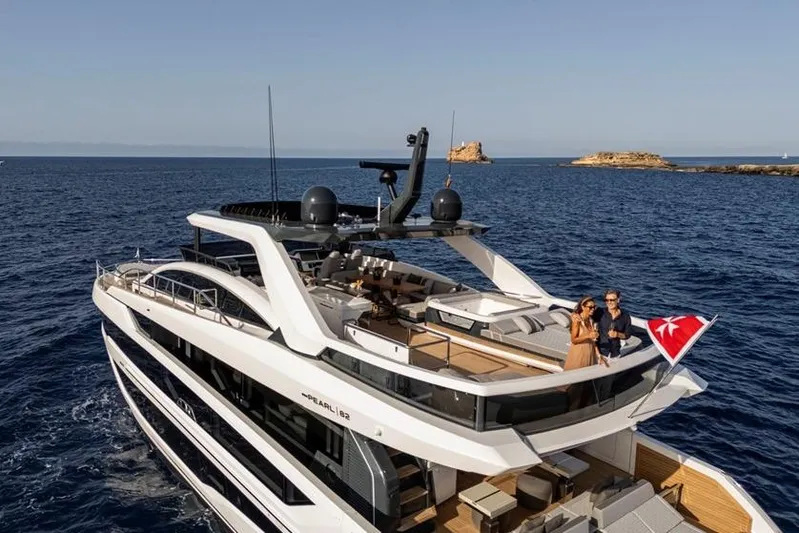 Pearly Spencer Yacht Photos Pics Luxurious 2024 Pearl 82 yacht cruising on open sea with scenic island backdrop.