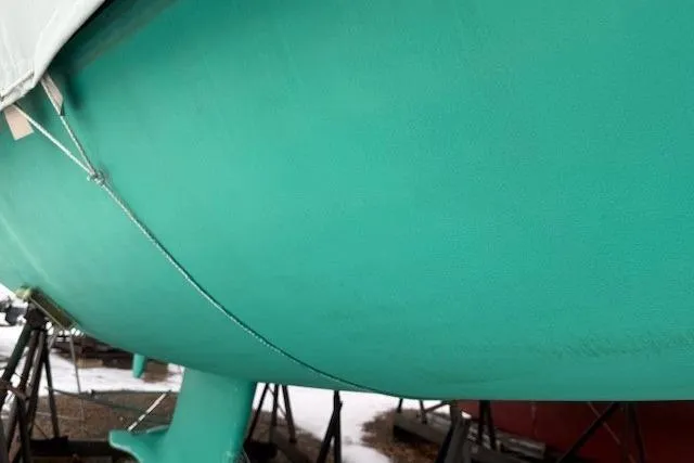 Star Yacht Photos Pics Turquoise hull of a 1998 Sabre 402 sailboat on stands, partially covered.