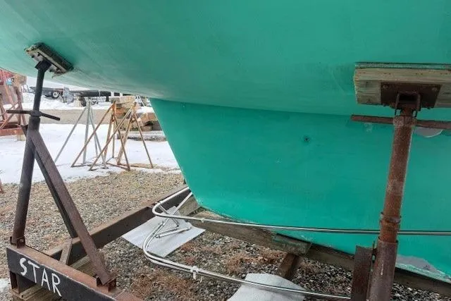 Star Yacht Photos Pics Green hull of a 1998 Sabre 402 sailboat on a stand, labeled "STAR."