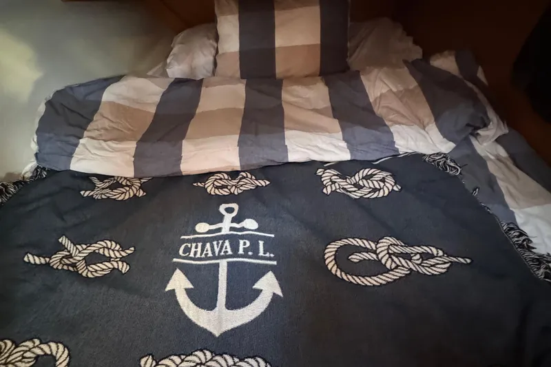 Squeeze De Citron Yacht Photos Pics Cozy bed with nautical-themed blanket on a 2023 Dufour 37 yacht.
