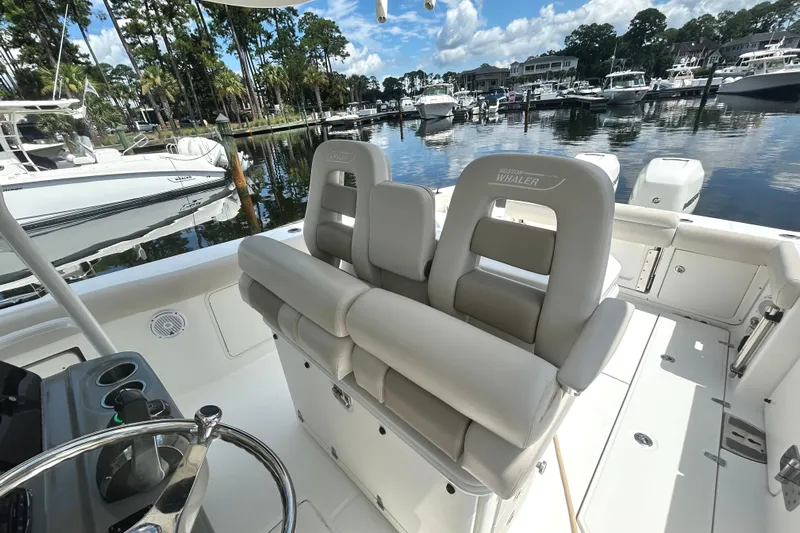  Yacht Photos Pics 2017 Boston Whaler 330 Outrage boat interior with luxurious seating in a marina setting.